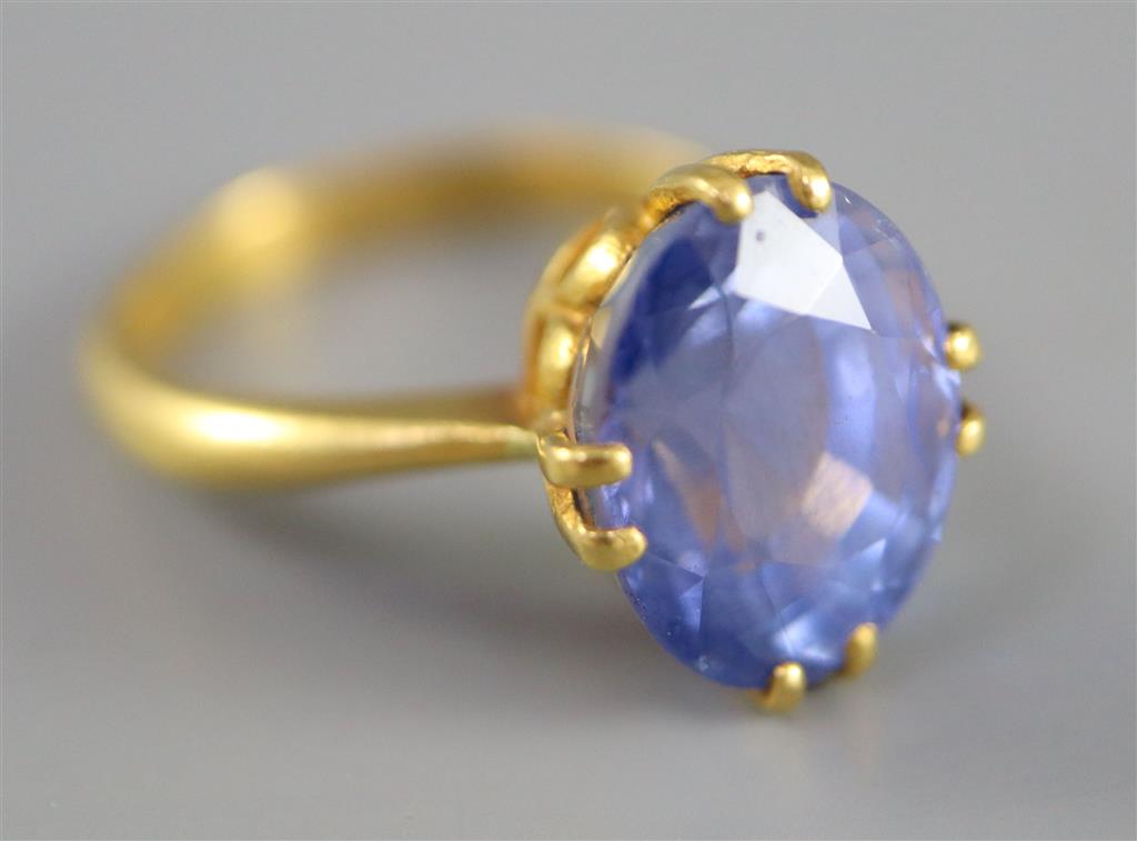 A gold (stamped 24k) and solitaire oval cut Ceylon sapphire set ring,